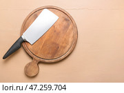 Разделочная доска с тесаком для мяса на бежевом фоне. Стоковое фото, фотограф Pixel_shot / Фотобанк Лори
