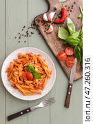 Тарелка вкусной пасты пенне с томатным соусом на деревянном фоне. Стоковое фото, фотограф Pixel_shot / Фотобанк Лори