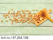 Доска и ложка с вкусными фисташками на зеленом деревянном фоне. Стоковое фото, фотограф Pixel_shot / Фотобанк Лори