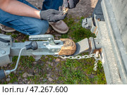 A man attaches a trailer to a car, securing safety chains to the trailer's hitch and drawbar. Стоковое фото, фотограф Коханова Наталья / Фотобанк Лори