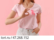 Молодая женщина в футболке с розовой лентой показывает ОК на цветном фоне. Концепция осведомленности о раке молочной железы. Стоковое фото, фотограф Pixel_shot / Фотобанк Лори