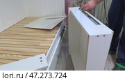 The man is assembling pull-out shelves for the sofa bed. He attaches telescopic slides to the side surfaces of the shelf. Self-assembly of furniture. Стоковое видео, видеограф Vadzim Yakubovich / Фотобанк Лори