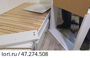 The man is assembling pull-out shelves for the sofa bed. He installs the bottom of the shelf. Стоковое видео, видеограф Vadzim Yakubovich / Фотобанк Лори