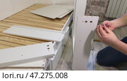 The man is assembling pull-out shelves for the sofa bed from wooden panels. He installs furniture cam locks. Стоковое видео, видеограф Vadzim Yakubovich / Фотобанк Лори