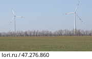 Wind turbines spin energetically against a blue sky, harnessing renewable energy in the countryside field on spring. Supporting farmers through innovative practices. Green and renewable power concept. Стоковое видео, видеограф Ирина Михайличенко / Фотобанк Лори