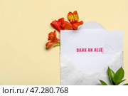 Открытка с текстом DANK AN ALLE, конвертом и цветами на бежевом фоне. Стоковое фото, фотограф Pixel_shot / Фотобанк Лори