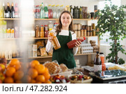 Teen girl seller stands in trading hall of store with goods in hand. Стоковое фото, фотограф Яков Филимонов / Фотобанк Лори