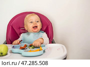Baby food. The first meal. Feeding the baby. A cute little kid eats vegetables. Healthy food. The child is sitting on a high chair for feeding. Fresh vegetables and fruits. Стоковое фото, фотограф Photojuli / Фотобанк Лори