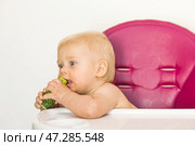 Baby food. The first meal. Feeding the baby. A cute little kid eats vegetables. Healthy food. The child is sitting on a high chair for feeding. Fresh vegetables and fruits. Стоковое фото, фотограф Photojuli / Фотобанк Лори