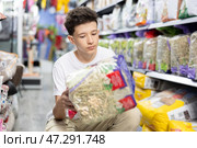 Teen boy take hay from shelf in pet store. Стоковое фото, фотограф Яков Филимонов / Фотобанк Лори