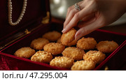 Delicious golden bites being picked from a luxurious red velvet box. Вкуснейшие золотые кусочки, которые достают из роскошной коробки из красного бархата. Стоковое AI-изображение, AI-художник Katsiaryna Repich / Фотобанк Лори