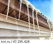 Danger of icicles forming on a roof due to melting snow during winter and spring transition. Стоковое фото, фотограф Кривошеина Елена Леонидовна / Фотобанк Лори