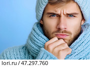 Молодой мужчина в голубом вязаном свитере, шарфе и шапке. Портрет на синем фоне. Space for text. Стоковое AI-изображение, AI-художник Щеголева Ольга / Фотобанк Лори