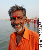 A man joyfully poses by the Ganges River in Varanasi, dressed in vibrant orange attire, as local rituals unfold around him under the warm sun Generative AI. Стоковое AI-изображение, AI-художник Юлия Петровская / Фотобанк Лори