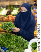Young Muslim woman in niqab choosing fresh cilantro on market. Стоковое фото, фотограф Яков Филимонов / Фотобанк Лори