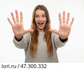A Joyful Young Woman Expressing Excitement With Her Hands Up, Indoors, Against a Plain Background During the Day. Стоковое AI-изображение, AI-художник Sergey Grishin / Фотобанк Лори