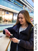 Happy Woman Browsing Her Phone While Shopping in an Upscale Mall Environment. Стоковое фото, фотограф Aleksandr Golubev / Фотобанк Лори