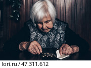 Portrait of an old woman counting money. The concept of old age, poverty, austerity. Стоковое фото, фотограф Matej Kastelic / Фотобанк Лори