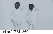 Fencing - two young women fencers putting on their protective helmets and aiming with swords in the camera. Стоковое видео, видеограф Константин Шишкин / Фотобанк Лори