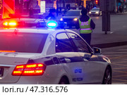 Сотрудники ДПС с автомобилем с включенным проблесковым маячком ведут патрулирование на улице в центре города Москвы, Россия (2017 год). Редакционное фото, фотограф Николай Винокуров / Фотобанк Лори