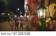 Glowing lantern illuminating blurred silhouettes along black sea waterfront in crimea, capturing twilight's warm urban ambiance. Стоковое видео, видеограф Mikhail Davidovich / Фотобанк Лори