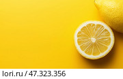 Bright yellow lemons on a vibrant backdrop showcasing fresh citrus cut in half, copy space. Свежие лимоны разложены на ярко-желтой поверхности: один целый лимон рядом с разрезанным пополам, раскрывая его сочную внутренность и пикантную привлекательность. Стоковое AI-изображение, AI-художник Katsiaryna Repich / Фотобанк Лори