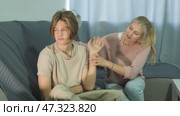 Portrait of unhappy teenage son after discord with mother sitting at sofa indoors. Стоковое видео, видеограф Яков Филимонов / Фотобанк Лори