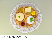 Cheese plate with three kinds of cream cheeses with basil, mandarin, honey, fruit jam and walnuts on round wooden plate on handmade crocheted lace napkin. Healthy organic food. Flat lay, top view. Стоковое фото, фотограф Виктория Катьянова / Фотобанк Лори