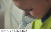 The kid is breathing with an inhaler and watching a cartoon. Стоковое видео, видеограф Mikhail Davidovich / Фотобанк Лори