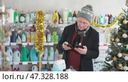 In X mas atmosphere, senior man sniffs fragrance of perfume, chooses scent spray with pleasant smell. Стоковое видео, видеограф Яков Филимонов / Фотобанк Лори
