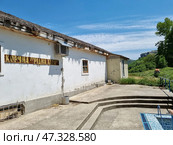 White plastered walls, a thatched roof (or imitation of it), simple wooden windows, an air conditioner on the wall — all this creates an atmosphere of rural comfort and authenticity.In the background are green hills, forest and mountains, which give the place privacy and natural beauty. Probably, this place is somewhere in Crimea or in the south of Ukraine, not far from tourist routes and attractions. Стоковое фото, фотограф Анна Кривицкая / Фотобанк Лори