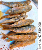 Fried red mullet, neatly piled on a plate. Small golden-brown fish with a crispy crust are a traditional and very aromatic dish, especially popular on the coast. On the side you can see a slice of lemon, which is usually used to give the fish a light citrus freshness. This dish evokes memories of the sea, vacations and warm winds. Стоковое фото, фотограф Анна Кривицкая / Фотобанк Лори