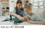 Close-up of hands creating custom jewelry with resin. Child and parent work together, pouring vibrant resin into tiny molds. Handmade art project helps develop creativity, patience, fine motor skills. Стоковое видео, видеограф Енваев Андрей / Фотобанк Лори