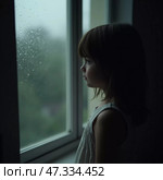 A young girl stands at the window, observing raindrops trickle down the glass. Her expression is thoughtful, hinting at a world of imagination on a serene, rainy day Generative AI. Стоковое AI-изображение, AI-художник Юлия Петровская / Фотобанк Лори