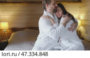Mature couple in a white bathrobes hugging each other kissing at home bedroom. Intimate Moment. Tender embrace shared between a loving middle age man and woman, husband and wife. Deep love. Vacation. Стоковое видео, видеограф Марина Демидюк / Фотобанк Лори