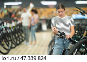 Female shopper inspecting mountain bicycle handlebars in store. Стоковое фото, фотограф Яков Филимонов / Фотобанк Лори