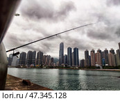 Lantau Island, Hong Kong - April 09, 2024: Fishing along the waterfront in Lantau, Hong Kong with urban skyline and dramatic clouds. Редакционное фото, фотограф Кривошеина Елена Леонидовна / Фотобанк Лори