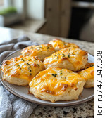 Aromatic and ruddy cheese buns laid out on a plate. They are fluffy, with a crispy golden crust and stretchy melted cheese on top. Sprinkled with fresh herbs, which adds appetizing flavor and aroma. The texture of the pastry looks tender and airy, with clearly defined layers. The atmosphere of coziness and home warmth - it seems as if the buns have just been taken out of the oven, and they are ready to please for breakfast or a snack. Стоковое AI-изображение, AI-художник Анна Кривицкая / Фотобанк Лори