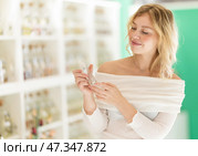 Woman customer chooses perfume in store, tests various fragrances, and selects right one. Стоковое фото, фотограф Яков Филимонов / Фотобанк Лори