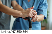 A healthcare professional provides support to a patient grasping a cane. The setting is warm and inviting, suggesting a home care environment focused on mobility assistance. Стоковое AI-изображение, AI-художник Sergey Grishin / Фотобанк Лори