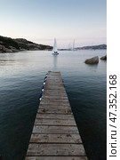 Wooden pier and sailboats sailing in evening calm sea of marvellous Porto Rafael, Costa Smeralda, Sardinia, Italy. Symbol for relaxation, wealth, leisure activity. Стоковое фото, фотограф Matej Kastelic / Фотобанк Лори