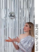 Engaging Moment of a Woman Juggling a Disco Ball in a Sparkly Outfit Indoors. Стоковое фото, фотограф Aleksandr Golubev / Фотобанк Лори