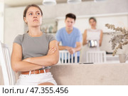Offended young woman sitting at kitchen during argument with husband and mother-in-law. Стоковое фото, фотограф Яков Филимонов / Фотобанк Лори