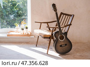 Guitar. Guitar chords. Acoustic guitar. Music. Musical background. An image of an acoustic guitar in a room with a retro armchair. Hard light. Shadows. Стоковое фото, фотограф Photojuli / Фотобанк Лори
