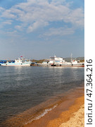 BAIKAL LAKE, SAKHIURTA VILLAGE, IRKUTSK REGION, RUSSIA - July 31, 2024: View of the pleasure boat pier in the village of Sakhiurta on a sunny day. Summer cruises and water trips. Scenic seascape. Редакционное фото, фотограф Виктория Катьянова / Фотобанк Лори