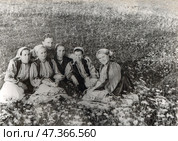 Девушки и юноша в русской народной одежде сидят на цветочном лугу, 1950-е гг. Стоковое фото, фотограф Retro / Фотобанк Лори