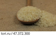 Вращающаяся ложка, наполненная рисовыми зернами, лежащими на мешковине. Крупный план. Стоковое видео, видеограф Александр Собко / Фотобанк Лори