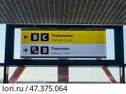 Информационные указатели в аэропорту Шереметьево, Москва. White and yellow signs at Sheremetyevo Airport, exit to Terminals B, C. Exit to Parking zone. Convenient informational navigation and markings for tourists and visitors. Редакционное фото, фотограф Ирина Михайличенко / Фотобанк Лори