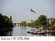 Река Большая Невка с видом на флаг - российский триколор, установленный на высоком флагштоке. Санкт-Петербург (2024 год). Редакционное фото, фотограф Сергей Афанасьев / Фотобанк Лори