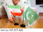 Young woman putting flags of Iran and Pakistan on table in office. Стоковое фото, фотограф Яков Филимонов / Фотобанк Лори